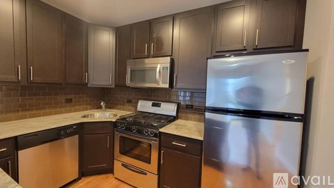 A kitchen with brown cabinets and a stainless steel refrigerator.