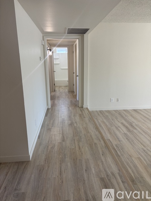 A long hallway with wood flooring and white walls.