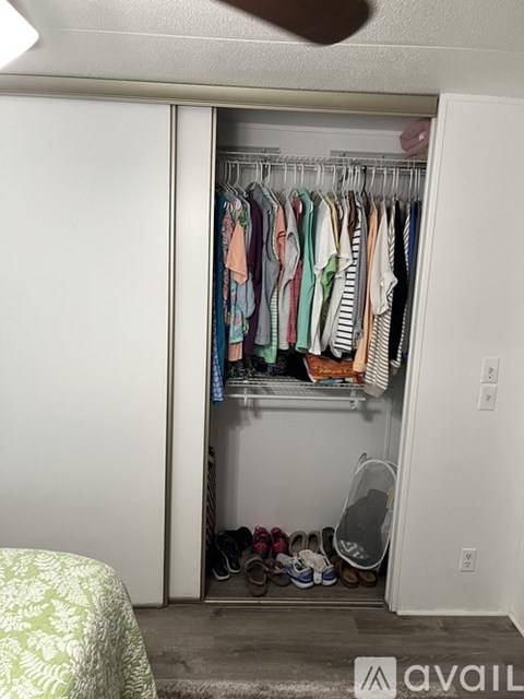A white closet with clothes and shoes.
