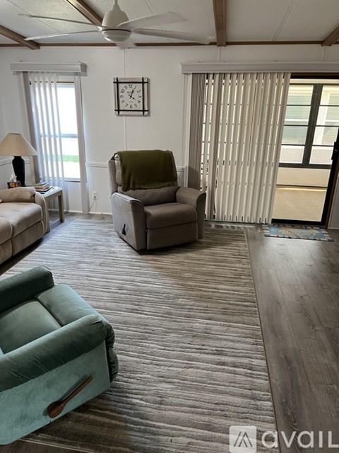A living room with a green chair and a white ceiling fan.