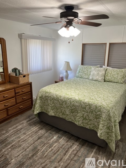 A bedroom with a bed, dresser, and ceiling fan.