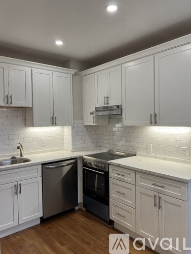 A kitchen with white cabinets and a wooden floor.