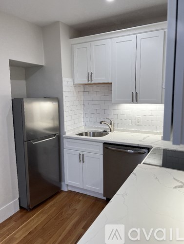 A kitchen with a stainless steel refrigerator and white cabinets.