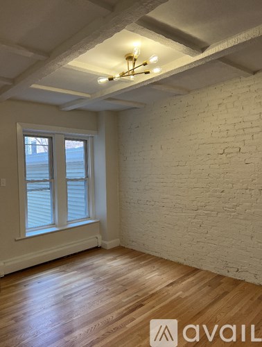 A room with wooden floors and a white brick wall.