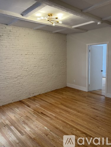 A room with wooden flooring and a white brick wall.