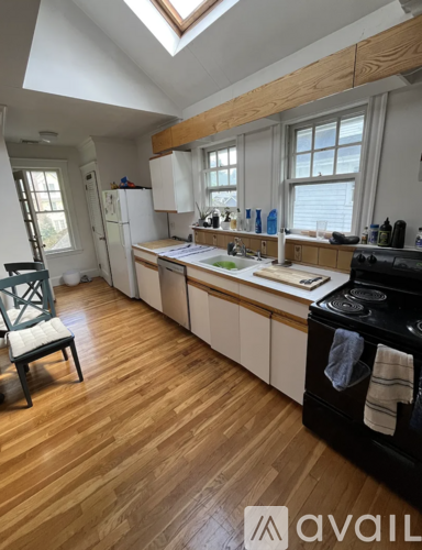 A kitchen with wooden floors and white cabinets.
