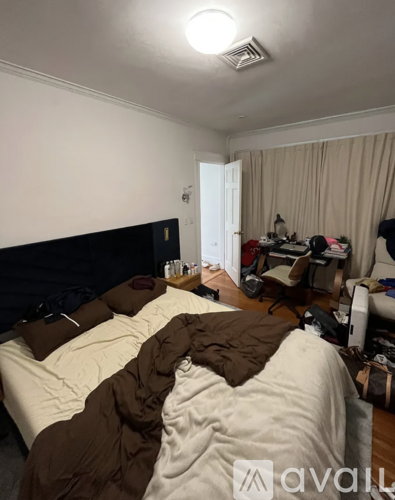 A bedroom with a bed covered in a white and brown comforter.