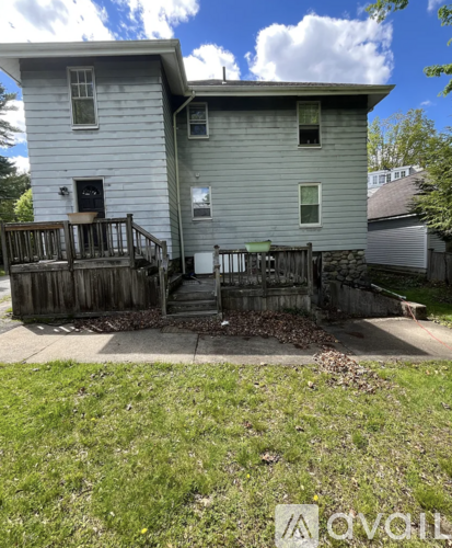 A house with a grey siding and a black door is surrounded by a wooden fence.