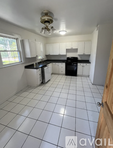 A kitchen with white cabinets and black appliances.