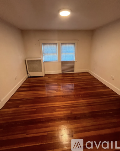 A room with wooden flooring and a window with blinds.