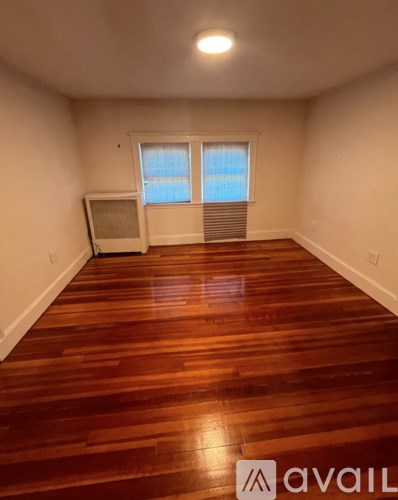 A room with wooden flooring and a window with blinds.