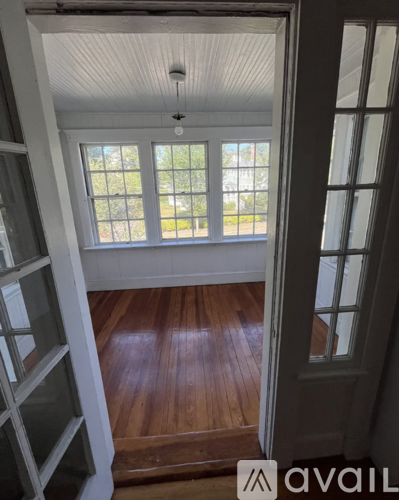 A room with a wooden floor and a window with a view of the outside.