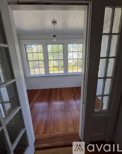 A room with a wooden floor and a window with a view of the outside.