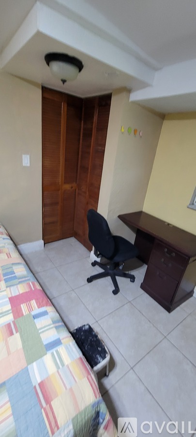A bedroom with a bed, a dresser, and a fire extinguisher on the wall.