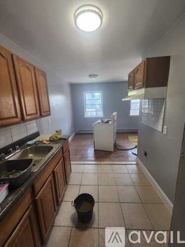 A kitchen with wooden cabinets and a black pot on the floor.