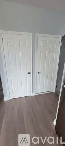 Two white doors with black handles in a room with wooden flooring.