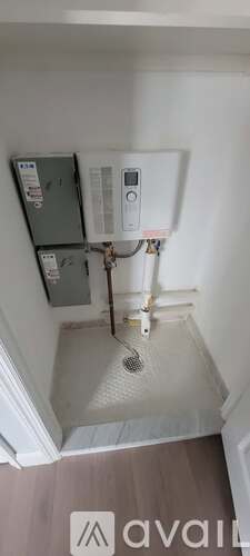A wall-mounted thermostat and a white electric heater are installed in a room.