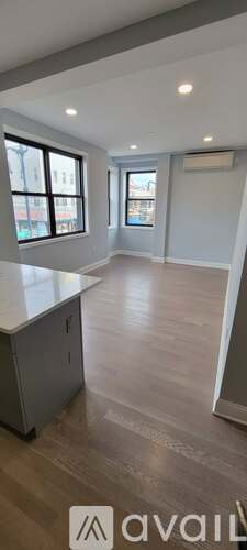A spacious room with wooden flooring and large windows.