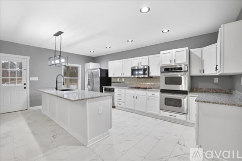 A modern kitchen with white cabinets and appliances.