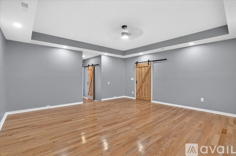 A spacious room with wooden flooring and two open doors.