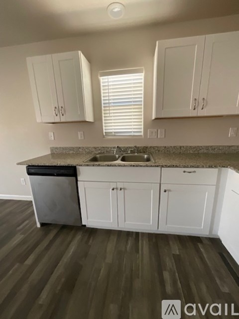 A kitchen with white cabinets and a granite countertop.