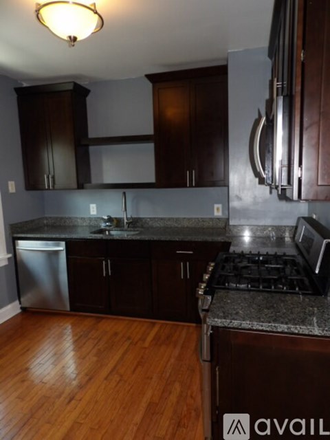 A kitchen with dark wood cabinets and a stainless steel dishwasher.