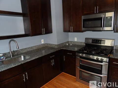 A kitchen with dark wood cabinets and a stainless steel stove top.