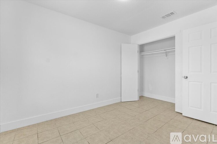 A room with a white door and a tiled floor.