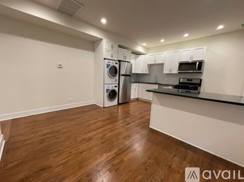 A room with wooden flooring and two windows.