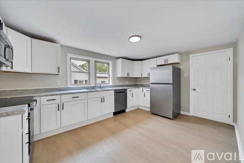 A kitchen with white cabinets and a stainless steel refrigerator.