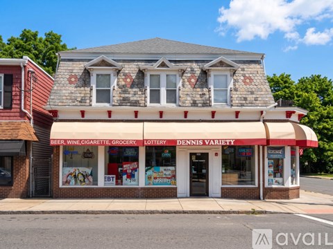 A storefront with a red and white striped awning advertises a variety of products including beer, wine, and cigarettes.