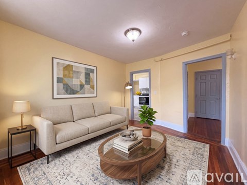 A living room with a beige couch, a coffee table, and a painting on the wall.