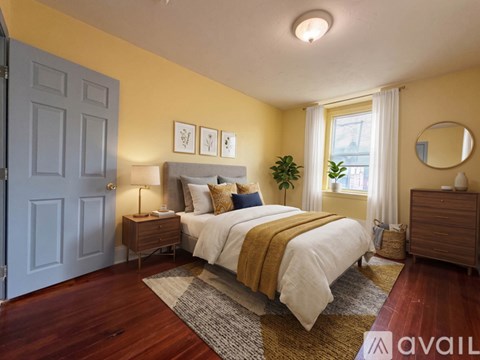 A bedroom with a bed, nightstand, and a mirror on the wall.