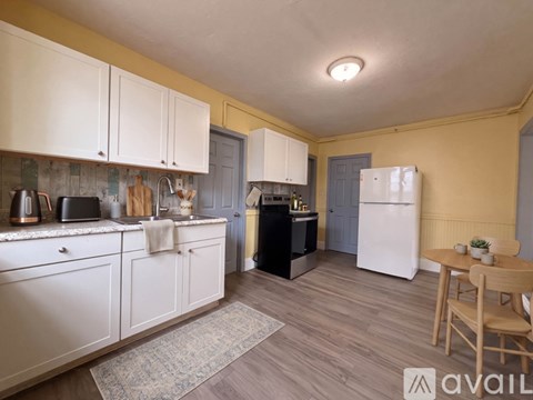 A kitchen with white cabinets and a wooden table.