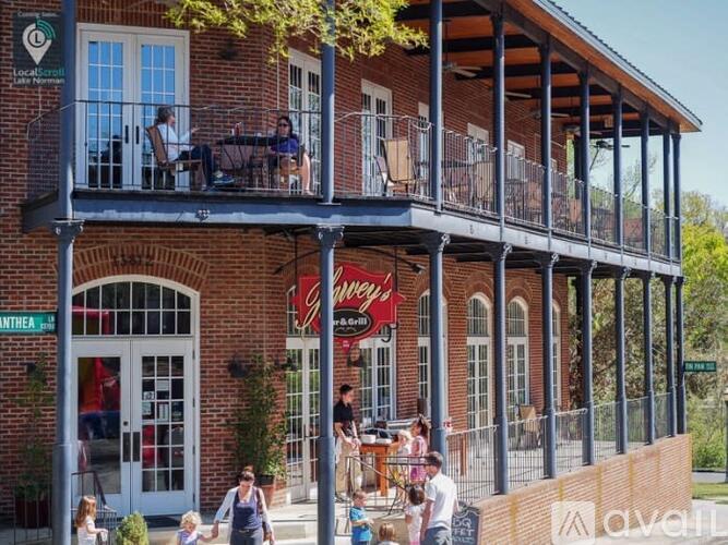 A group of people are sitting and standing on a balcony of a brick building.