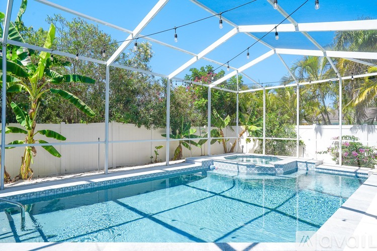 A pool with a white fence and trees in the background.