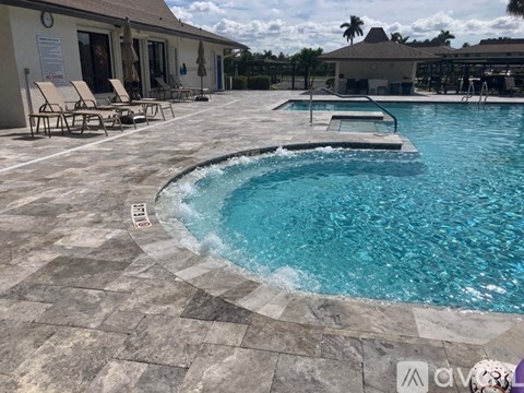 A swimming pool with a tiled edge and lounge chairs.