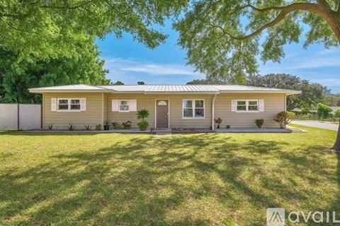 A house with a fence and trees in the background.