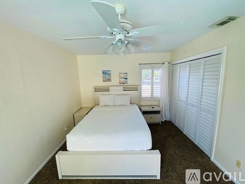 A bedroom with a bed, nightstand, and window with white shutters.