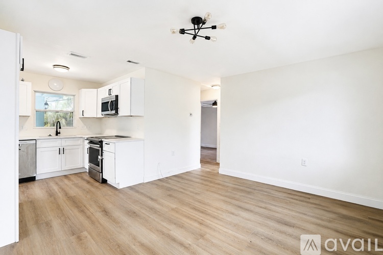 A kitchen with white cabinets and a wooden floor.