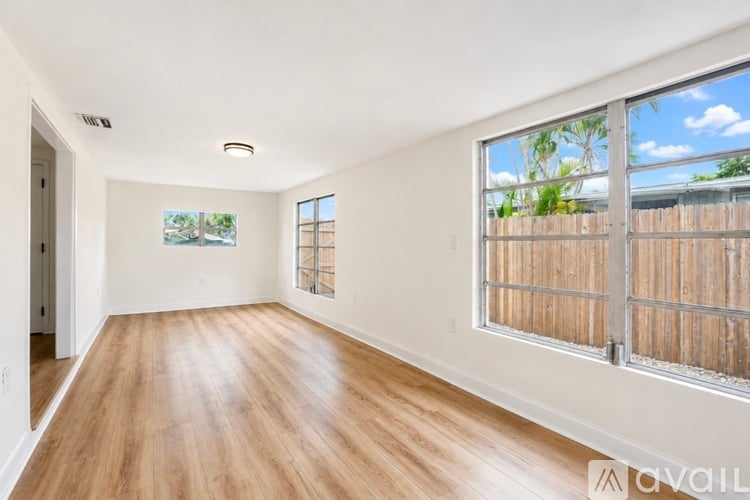 A spacious room with wooden floors and a large window.