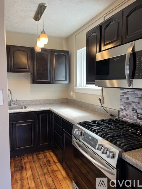 A kitchen with black cabinets and a stove top oven.
