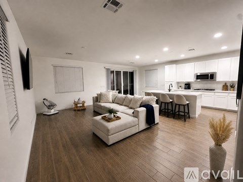 A modern living room with a white sofa set and wooden flooring.