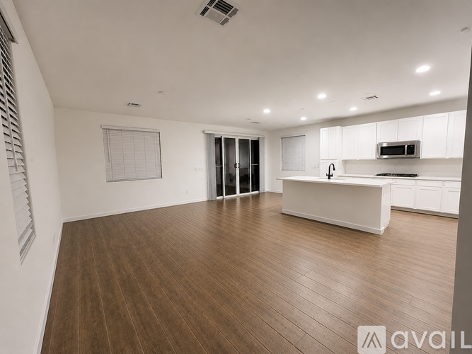 A spacious kitchen with white cabinets and a wooden floor.