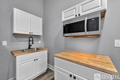 A kitchen with white cabinets and a wooden countertop.