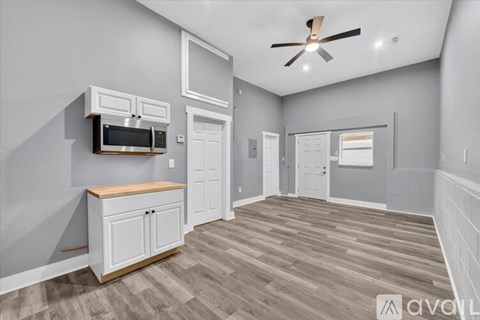 A spacious room with a ceiling fan and wooden flooring.