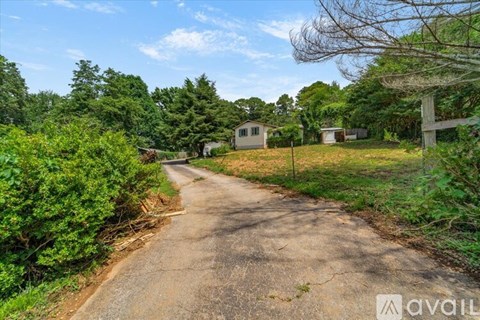 A rural road with a house on the side and trees surrounding the area.