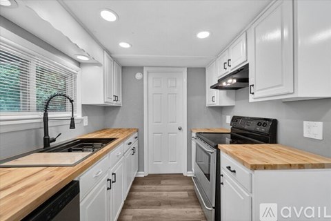 A kitchen with white cabinets and a wooden countertop.