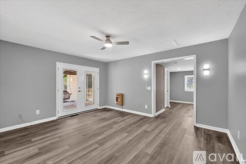 A spacious room with a ceiling fan and light wood flooring.