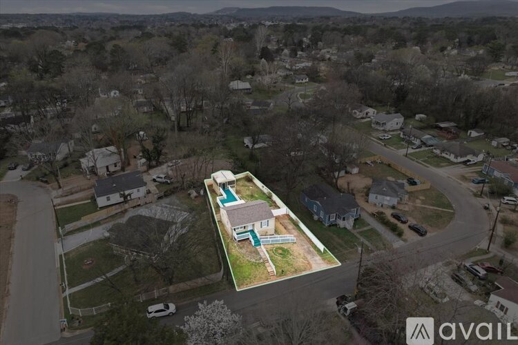 An aerial view of a neighborhood with a house that has a pool in the backyard.